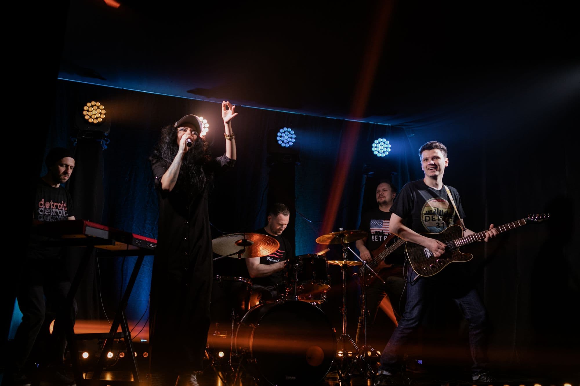 Liveband på en scene med gult scenelys og publikum foran
