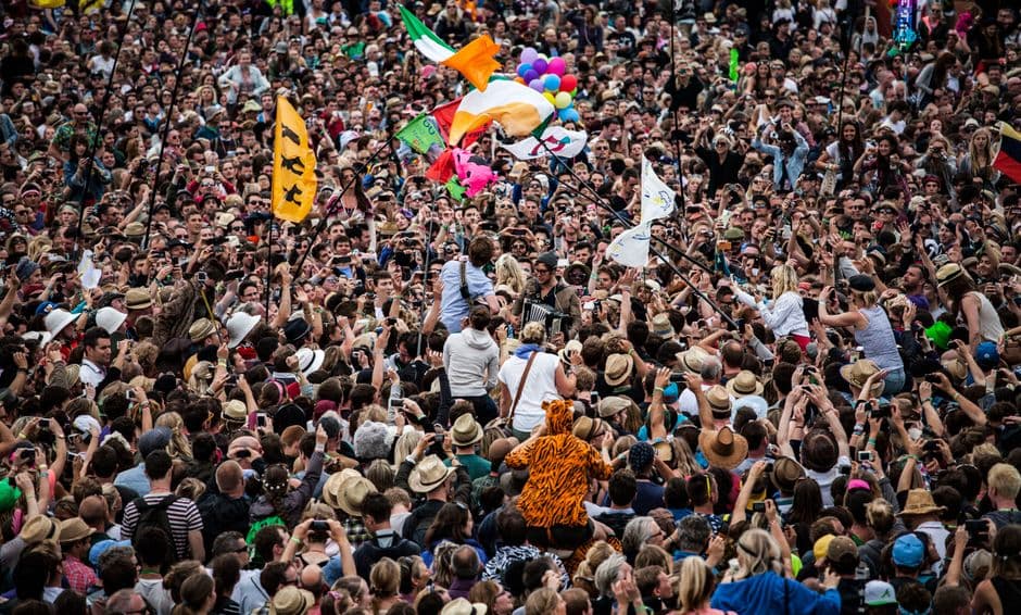 Stort publikum med flagg og ballonger foran en utendørs festivalscene