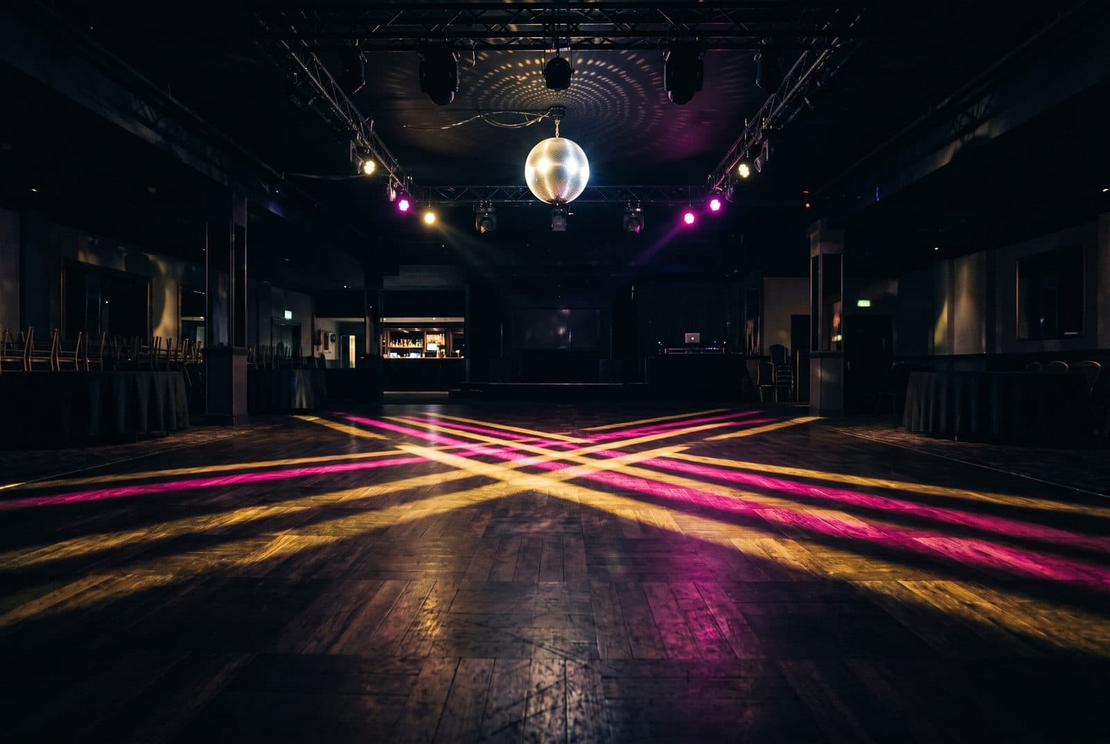 Tomt dansegulv med fargede lysstriper fra en discokule over