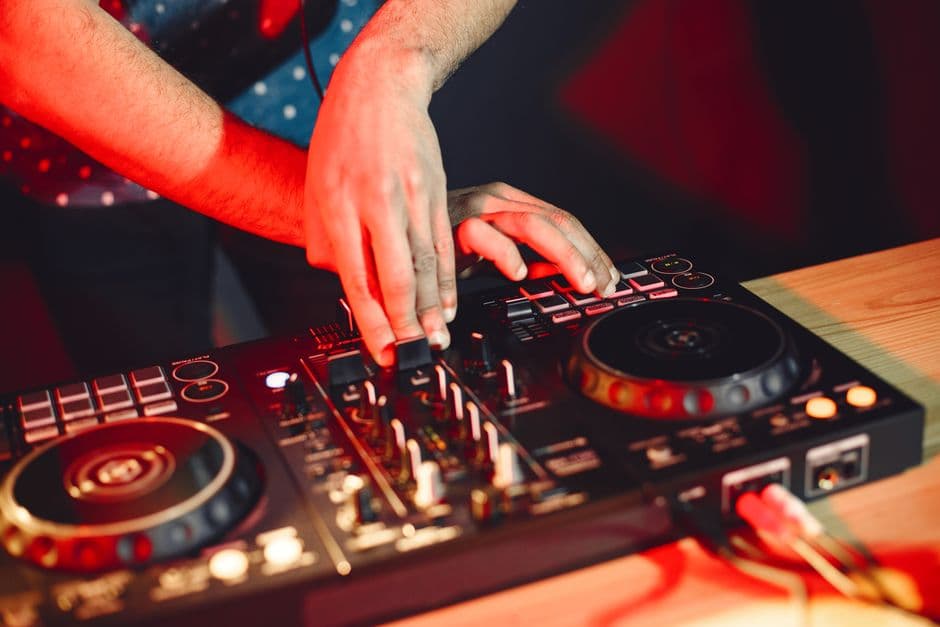 Hender som mikser på en DJ-controller i varmt rødt lys på et bord